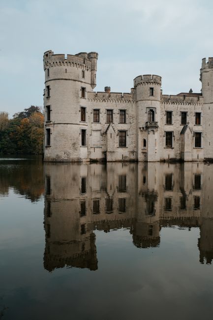 Breathtaking view of Bouchout Castle mirrored in a serene lake, showcasing Gothic architecture.