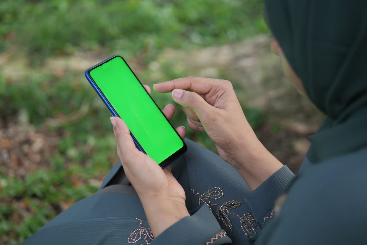 Dışarıda parkta oturan kişi akıllı telefonuyla oyun oynuyor