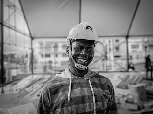 A Grayscale Photo of a Smiling Man Wearing a Hardhat
