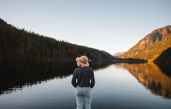 A Back View of a Woman in Gray Long Sleeves Standing Near the Lake