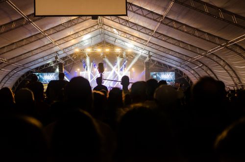 Free Captivating indoor concert with an energetic crowd enjoying live music under bright spotlights. Stock Photo
