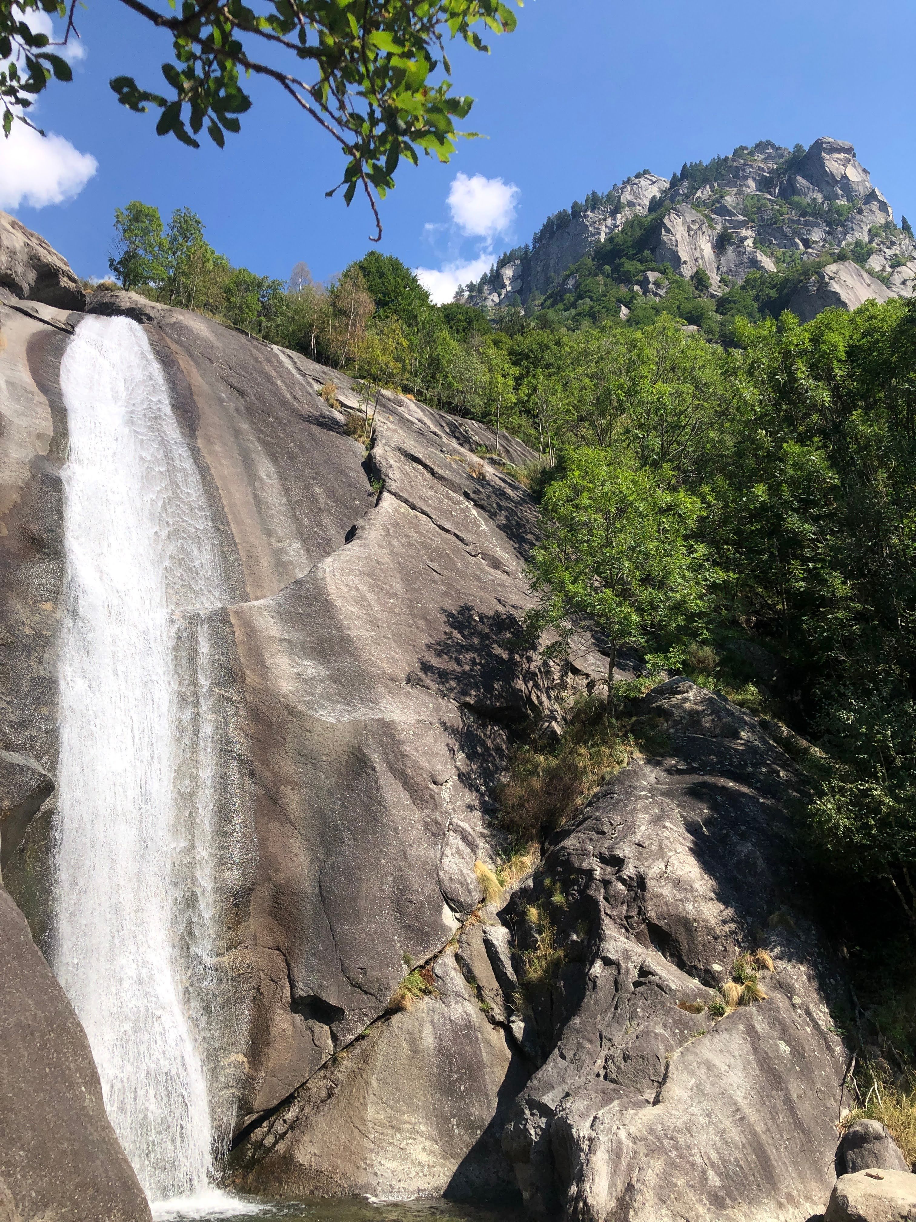 Discover the breathtaking waterfall in Val Masino, Lombardy, surrounded by lush greenery and towering rocks.