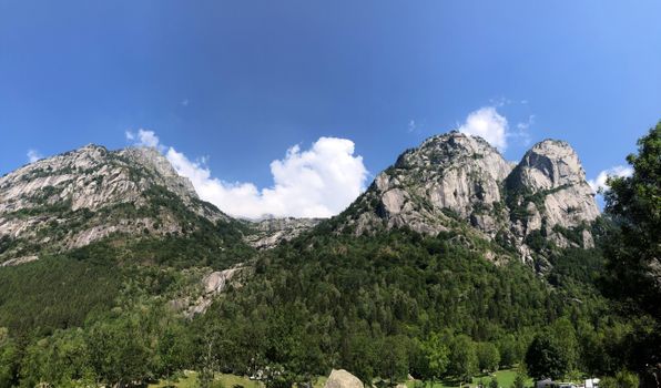 Stunning mountain landscape in Val Masino, Italy with clear skies and lush greenery.