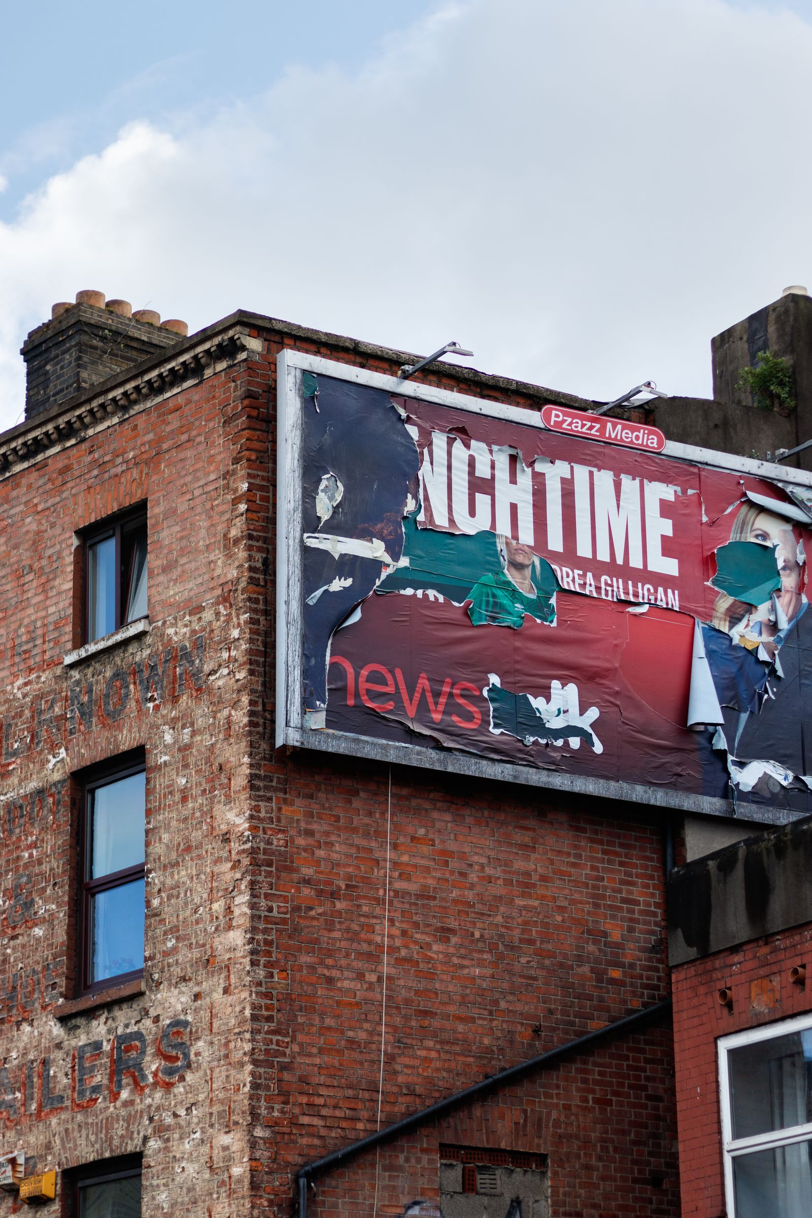 A torn billboard poster peels off the side of a building