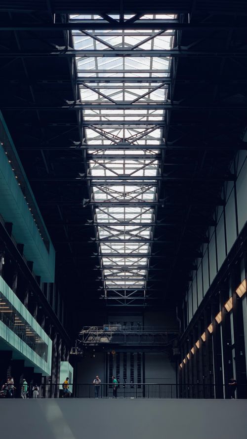 Free Architectural view of the Tate Modern Museum's interior hall with skylights and visitors in London, UK. Stock Photo