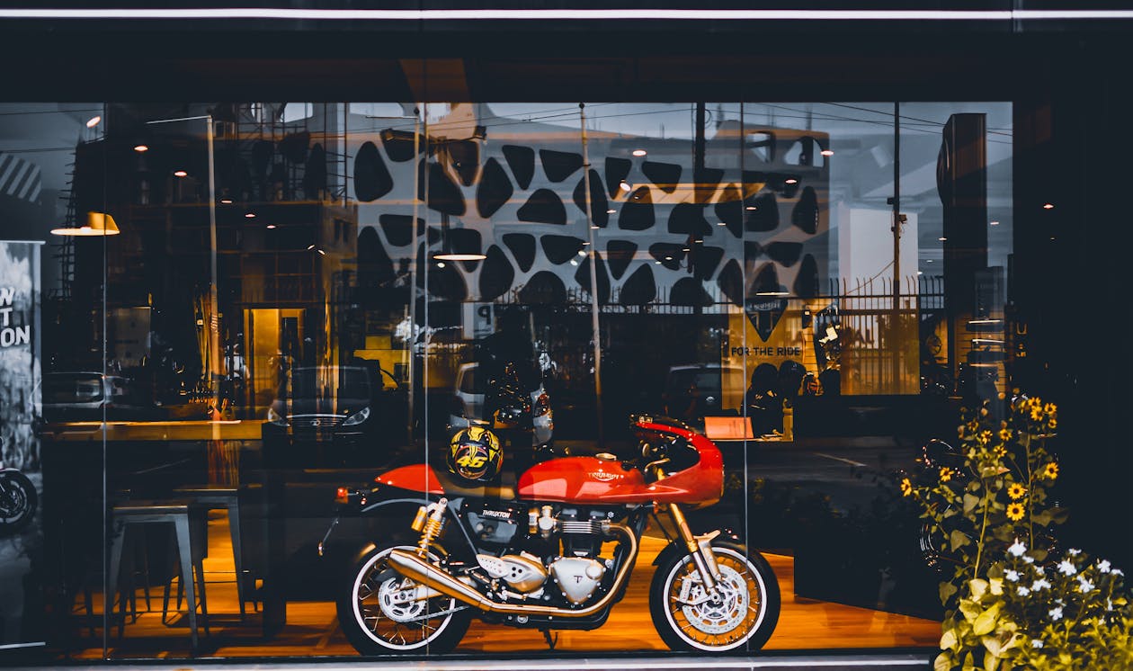 Red Standard Motorcycle With Gold Helmet Near Glass Wall