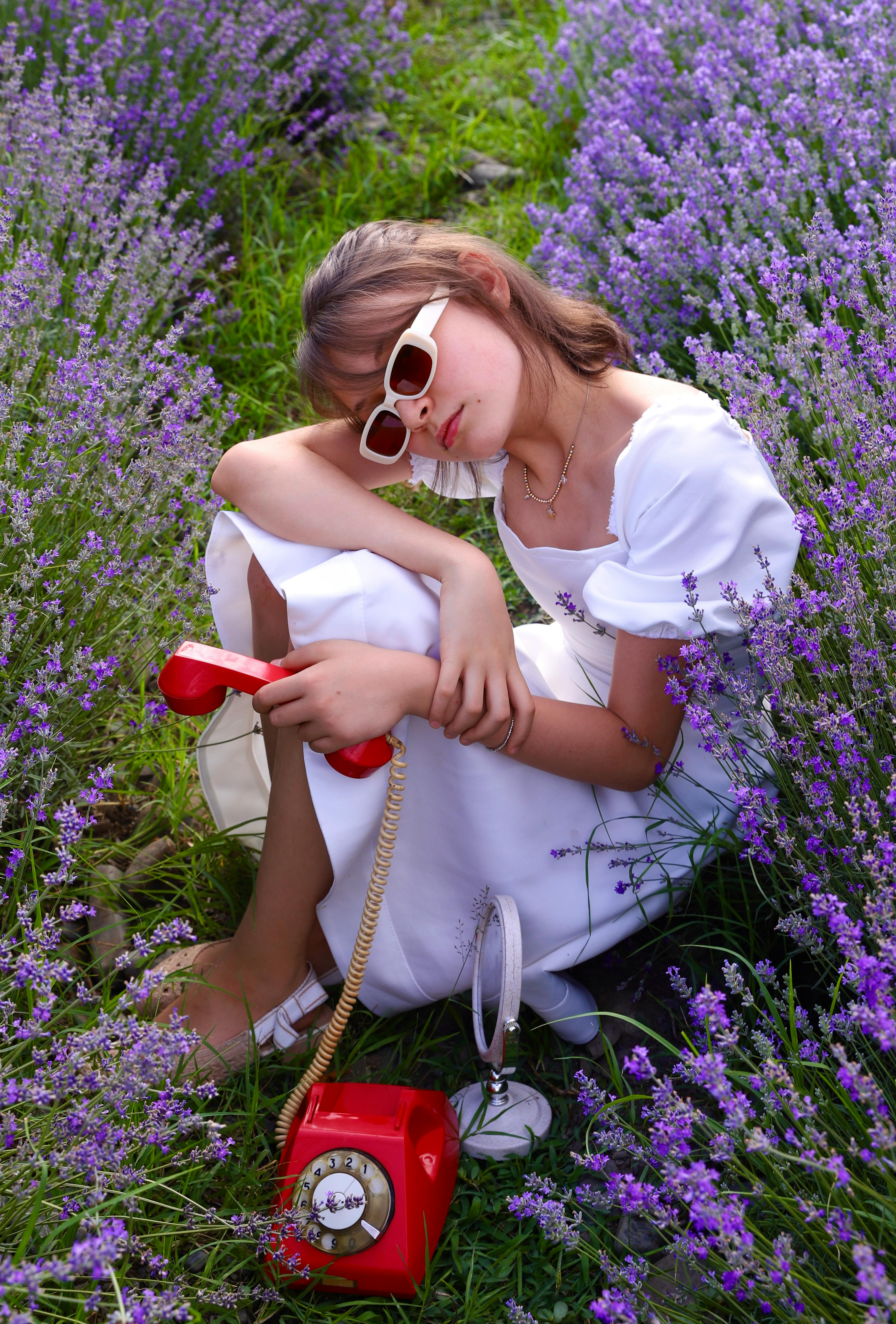 Woman in a white dress with red vintage phone in lavender field
