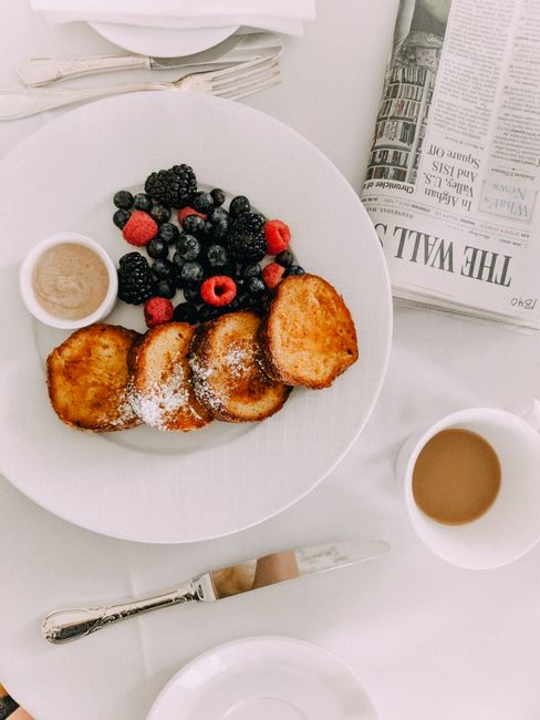 Chic breakfast setup with toast, mixed berries, coffee, and newspaper, offering a relaxing morning vibe.