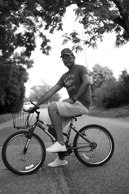 Grayscale Photo of Man Sitting on a Bicycle