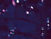 在神秘的黑暗背景下，发光气泡的特写镜头营造出梦幻般的氛围