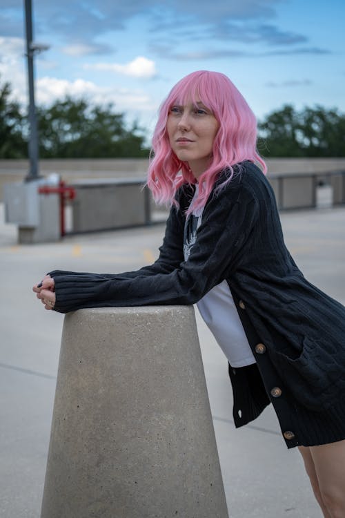 A Woman with Pink Hair Leaning on a Concrete Surface