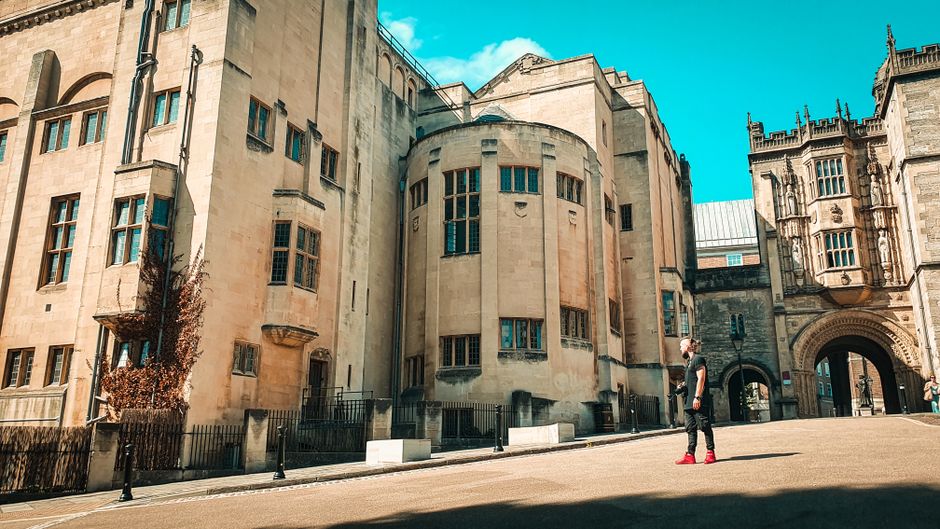 A man walking outside Bristol University campus featuring stunning Tudor revival architecture.