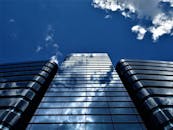 现代摩天大楼的低角度视图，玻璃立面反射着蓝天