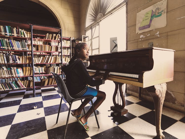 Girl Sitting On Chair In Front Of A Piano