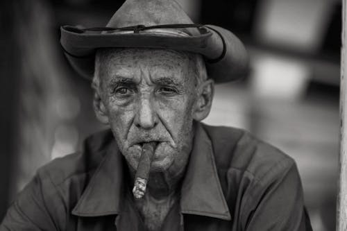 Безкоштовне стокове фото на тему «відтінки сірого, капелюх, куріння людини»