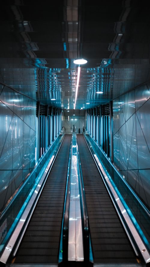 Free Low angle view of a modern, illuminated escalator inside a sleek architectural space. Stock Photo