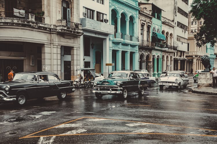 Vintage Cars Driving On Wet Asphalt Road