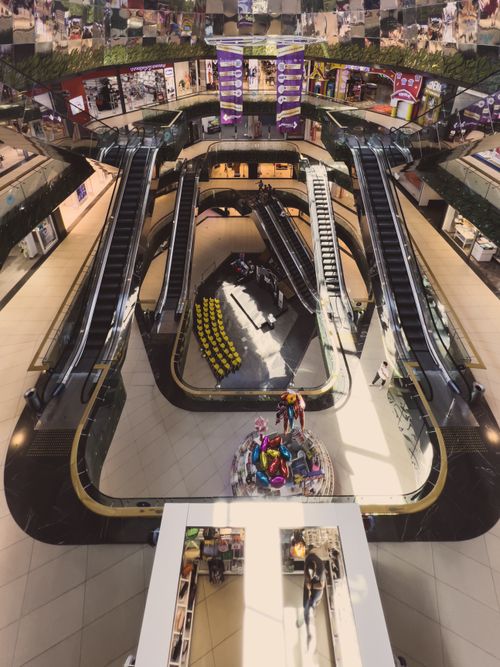 Free High angle view of a busy shopping mall interior with escalators and vibrant decor. Stock Photo