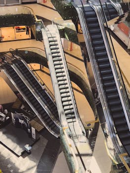 An overhead view of a modern shopping mall featuring multiple escalators and sleek interior design.
