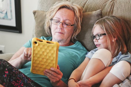 Woman Holding Tablet Lying Beside Girl Wear Eyeglasses