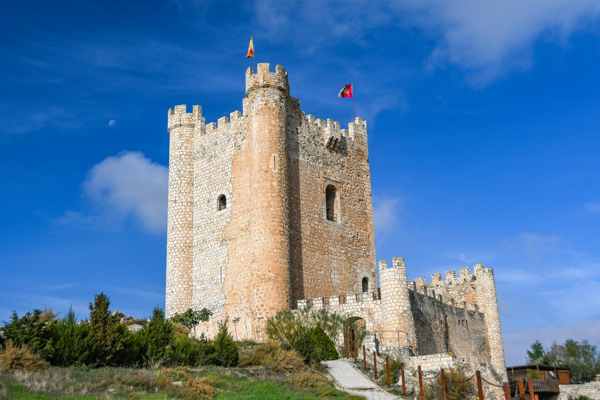 Explore the medieval architecture of Alcalá del Júcar castle under a clear blue sky.