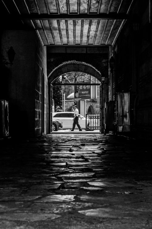 Free A man walks through an archway in an ancient Istanbul passage, captured in black and white. Stock Photo