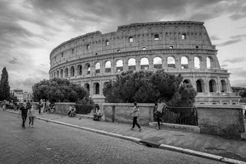 Grayscale Photo of People Walking Beside the Colosseum