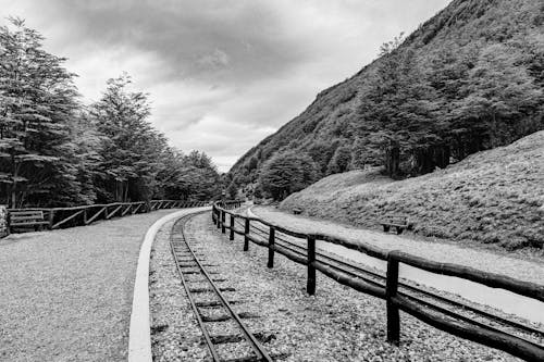 Grayscale Photo of Railway near Mountains