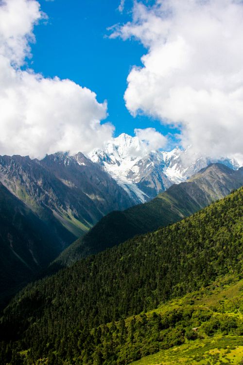Free A breathtaking mountain landscape with lush greenery and snow-capped peaks beneath a vibrant blue sky. Stock Photo
