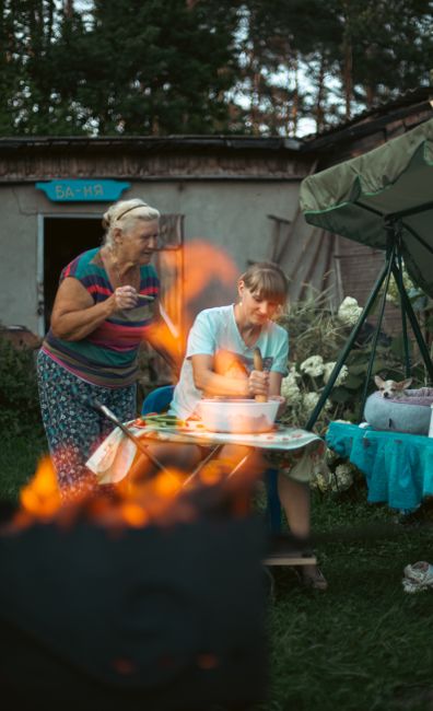 Photo by Вячеслав Ткачёв on Pexels A warm scene of a grandmother and granddaughter preparing food al fresco in a garden setting.