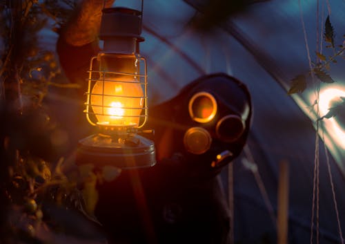 A Person with a Gas Mask Holding a Kerosene Lamp