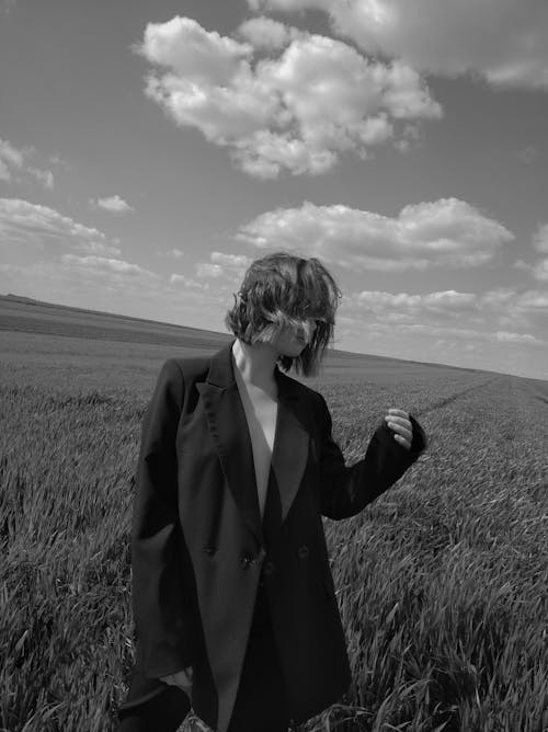 Grayscale Photo of Woman Wearing Blazer Standing on Grass Field
