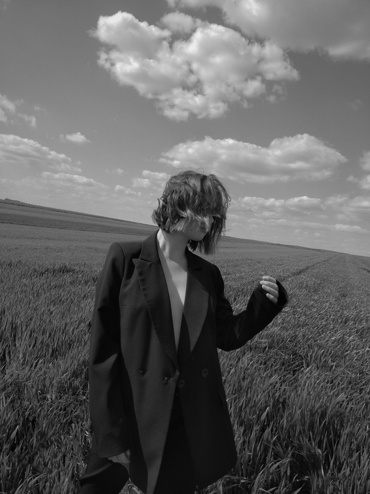 A woman wearing a blazer standing in a field — summer tailoring in natural light