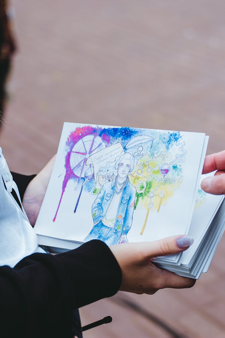 An Artist Holding A Stack Of Artwork