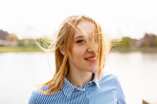 Woman Smiling While Standing Beside Body of Water