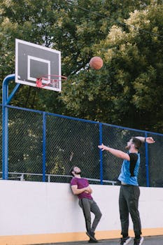 Two men enjoying a casual basketball game at an outdoor court on a sunny day.