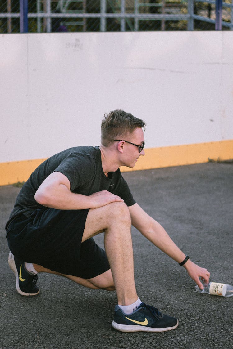 A Man In A Black Shirt Picking Up A Empty Bottle