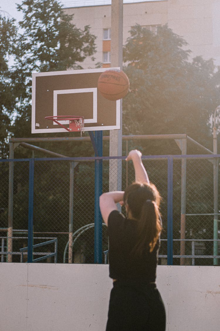 Back View Of A Woman Shooting A Basketball