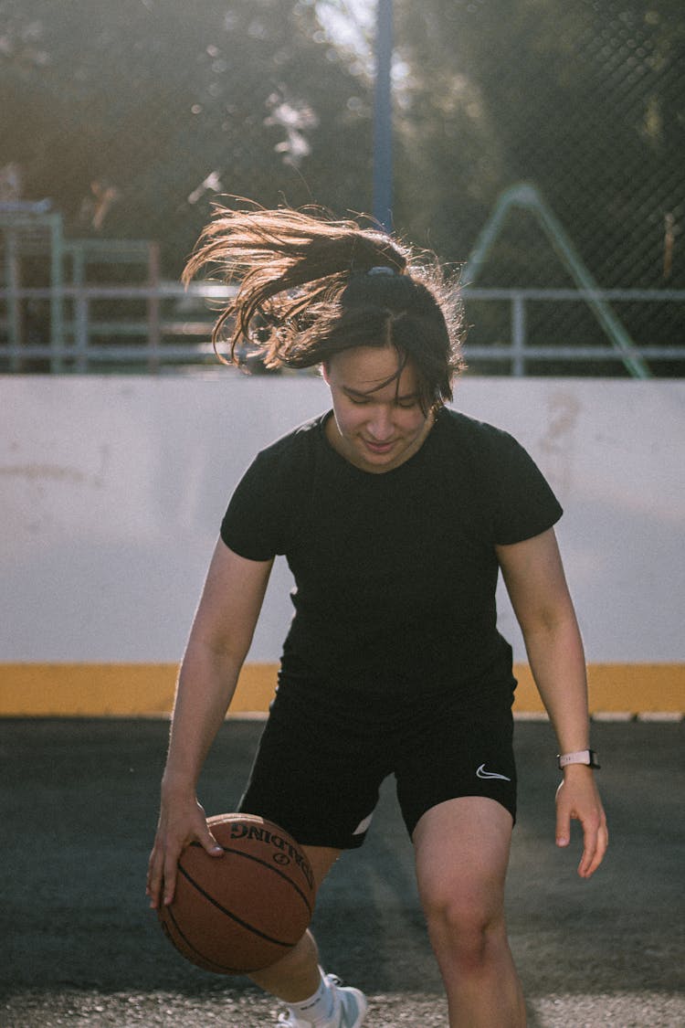 A Woman In A Black Shirt Dribbling A Ball