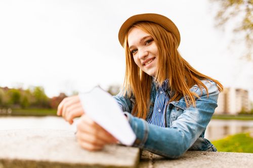 Free Smiling young woman with a hat enjoying a sunny day outdoors by the river. Stock Photo