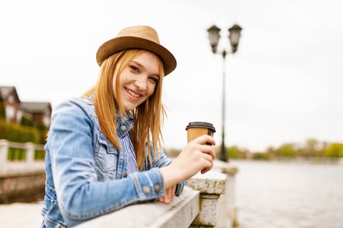 Woman Wearing Blue Denim Jacket While Holding Disposable Coffee Cup