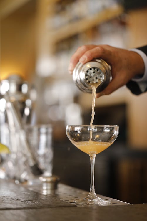 Pouring a Cocktail from a Cobbler Shaker into a Glass on the Bar