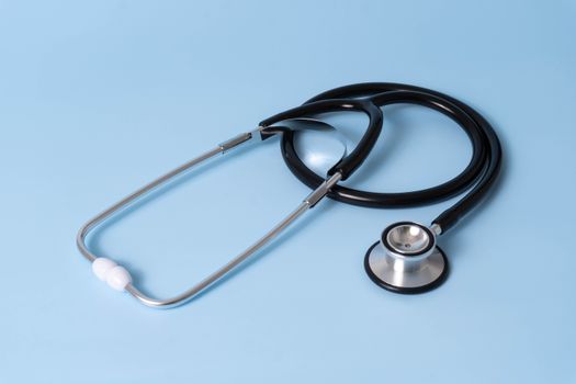 Close-up of a stethoscope laid on a light blue background, ideal for medical content.