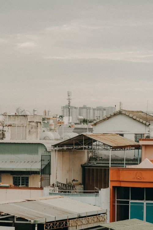 Free An aerial view of urban rooftops with skyscrapers in the distance under a cloudy sky. Stock Photo