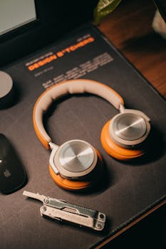 Modern headphones placed on a desk next to a multitool, creating a tech-savvy atmosphere.