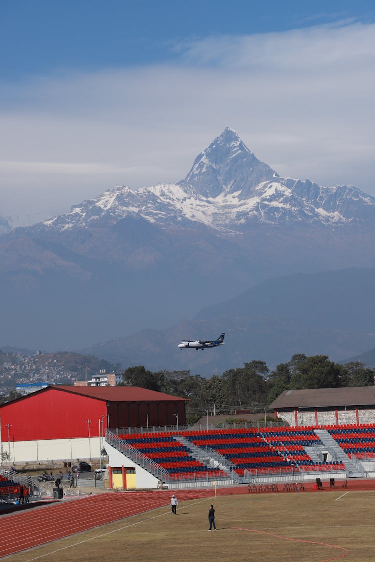 A View Of A Flying Airplane From A Stadium