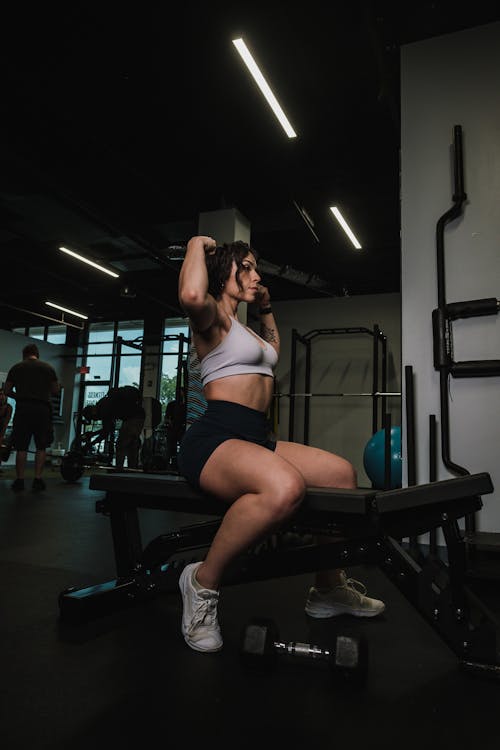 A woman in a black sports bra and shorts squatting on a white