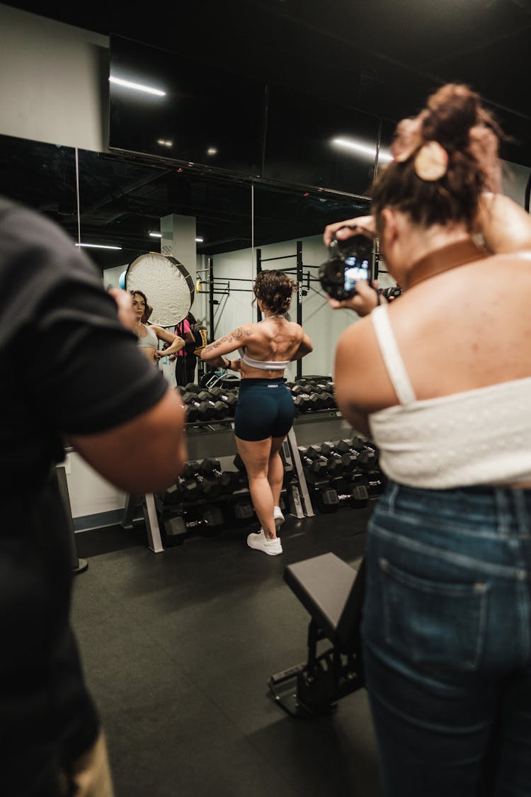 A Woman Looking At The Mirror While Posing In The Gym