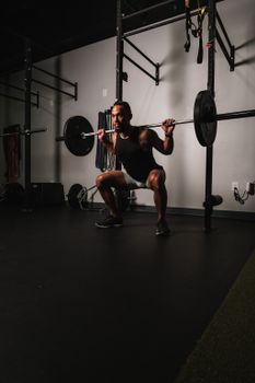 Muscular man performing squats with weights in gym, showcasing strength and fitness.