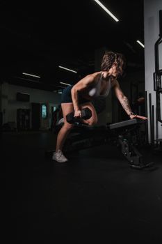 A fit woman lifting a dumbbell in an intense workout at a gym.